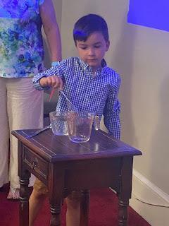 A boy transferring water from a cup to a jug during an experiment